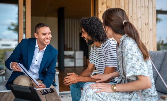 Three people happily chatting on a couch indoors.