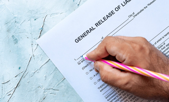 Person filling out a general release of liability form with a pencil.