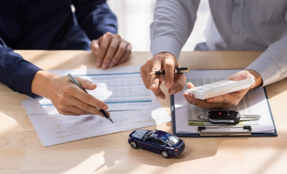 Two people reviewing insurance documents with a toy car on the table.